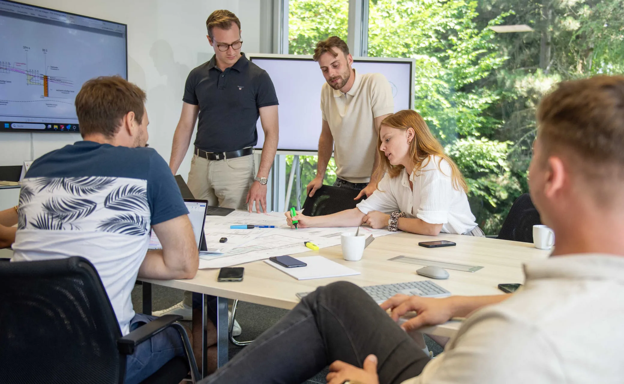 Mehrere Mitarbeiter, versammelt um einen Tisch, besprechen Projekt